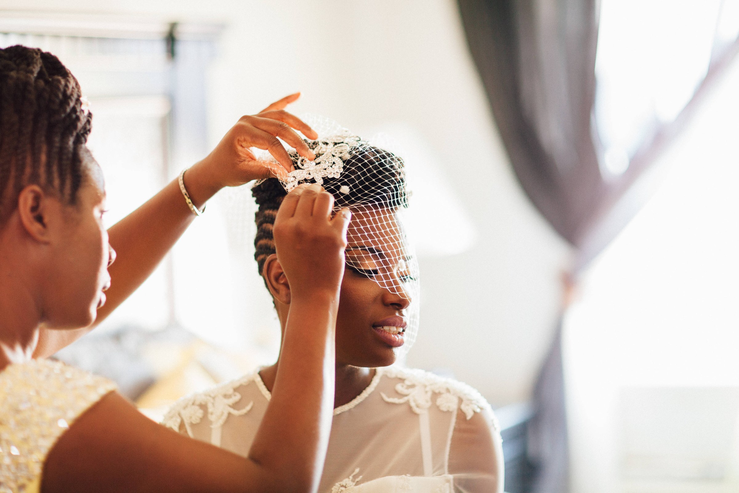 A bridesmaid sets a jewelled comb in a bride’s hair
