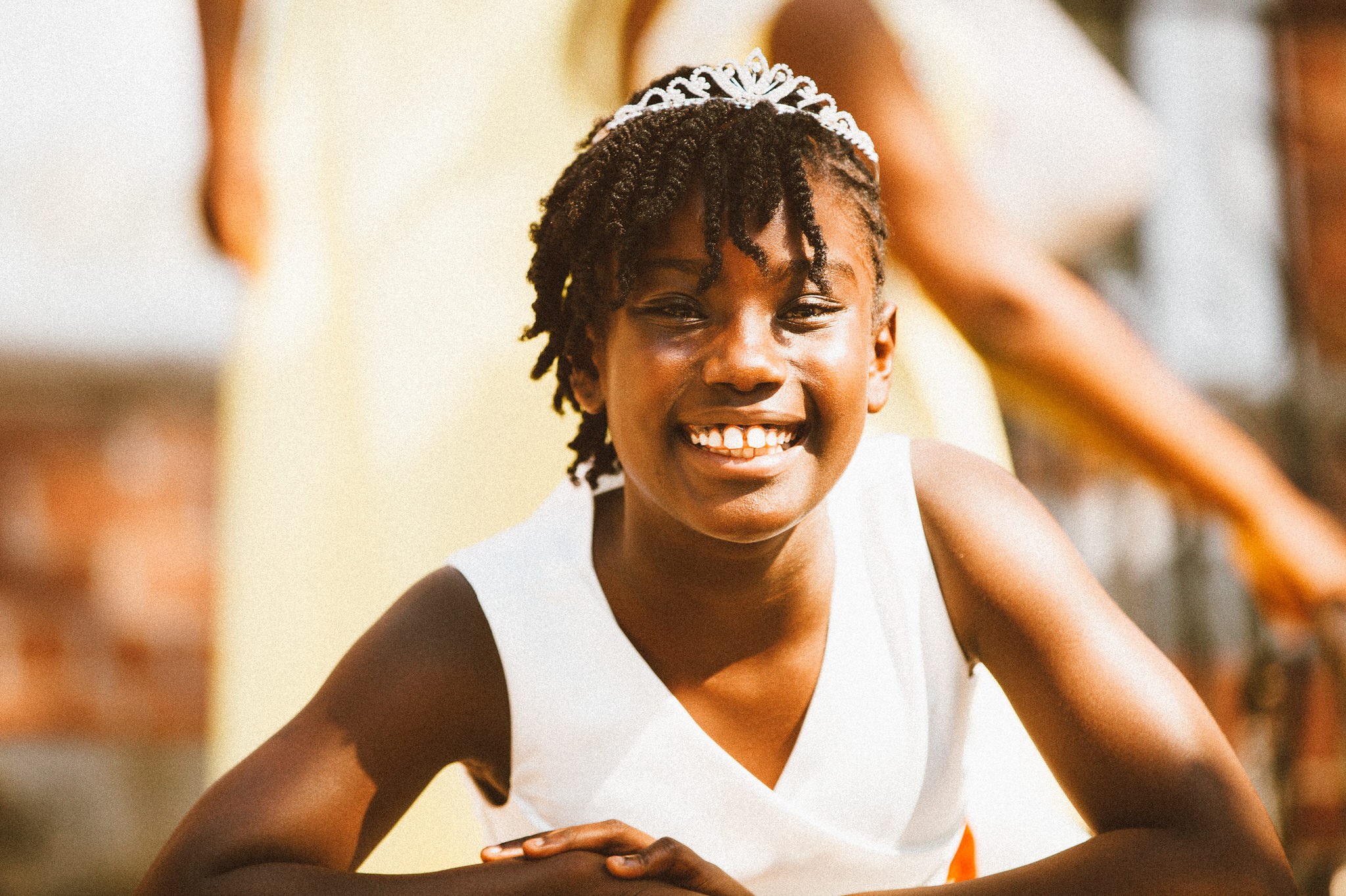 A smiling flower girl in a tiara