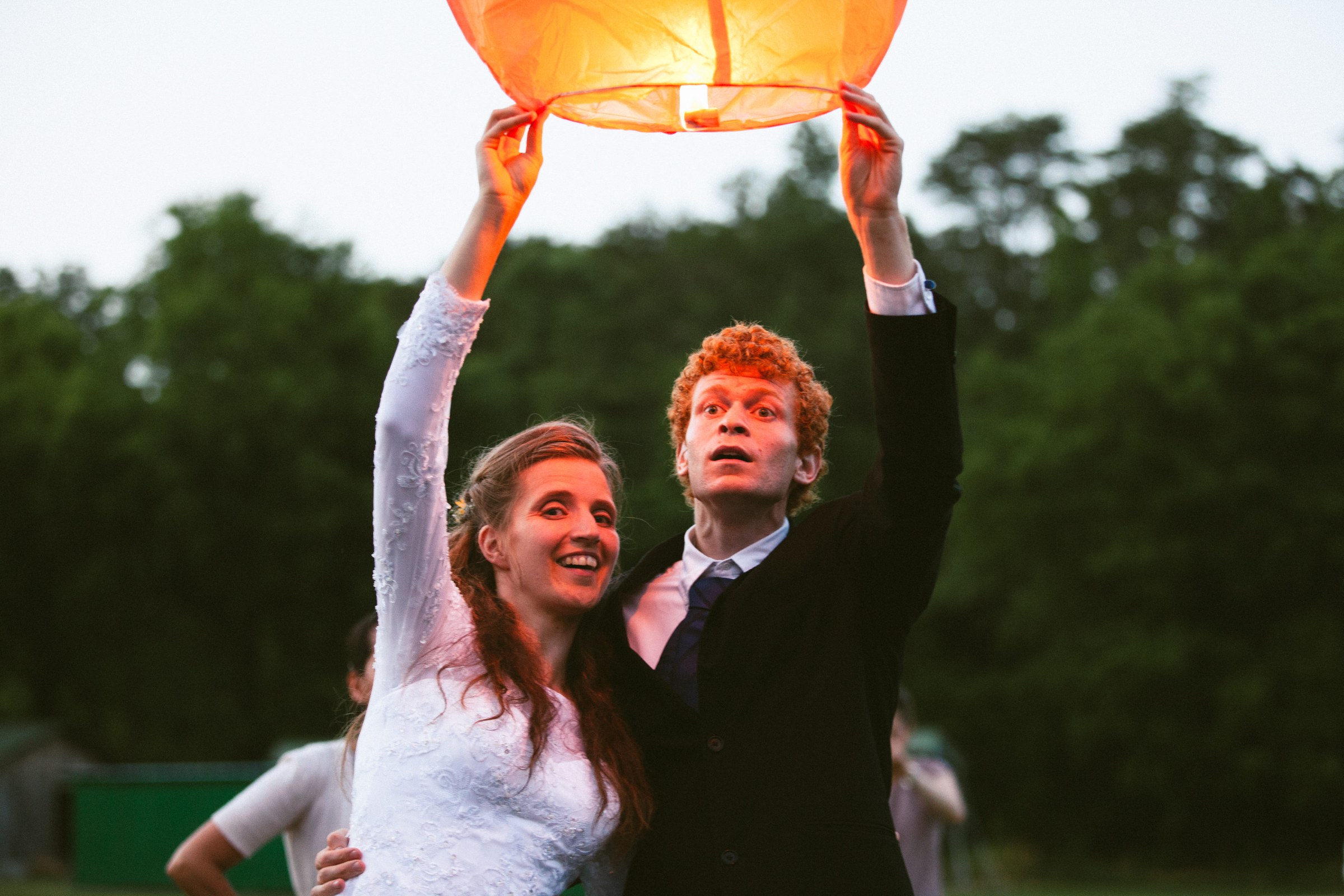 A couple release a glowing paper lantern at dusk