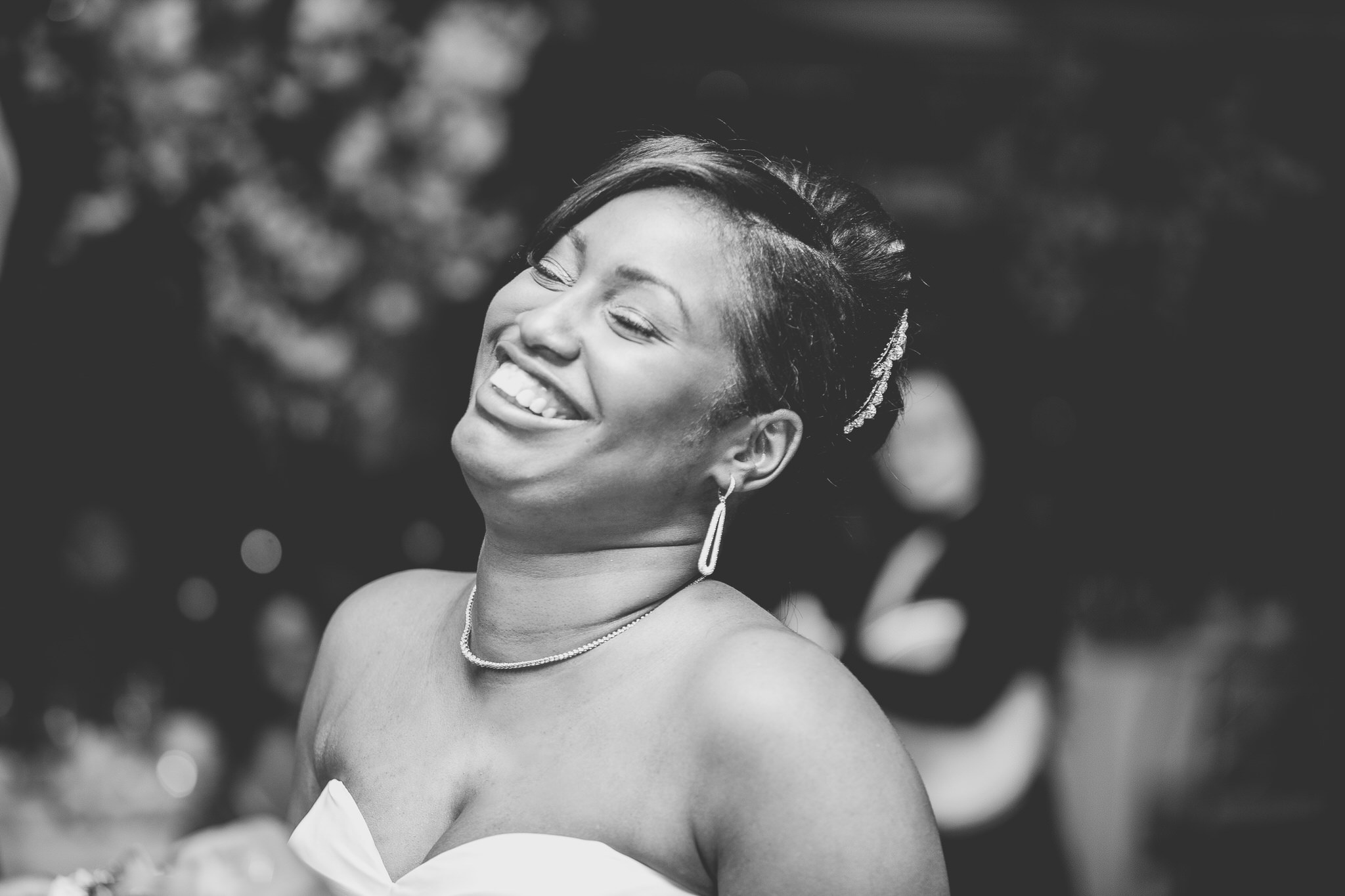 A bride laughing with her head thrown back, in black and white